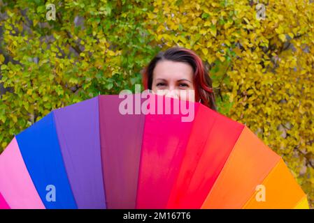 rainbow huge umbrella and girl one peeking out Stock Photo