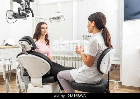 Female dentist explaining patient treatment during an appointment in dental clinic Stock Photo