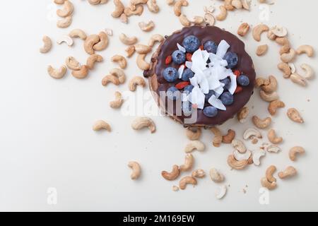 Vegan chocolate beet cake with blackberries, decorated with nuts and seeds coconut top view on white Stock Photo