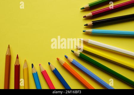 a set of colored pencils on a yellow table. Stock Photo