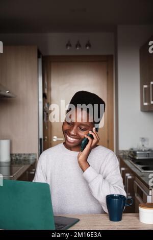 Content black female freelancer having phone conversation while working on computer Stock Photo