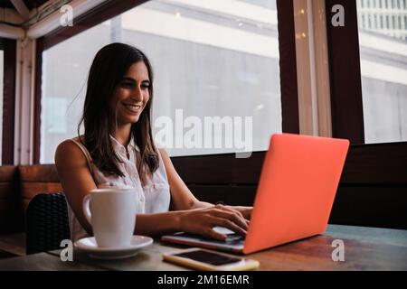 Woman working with a laptop sitting in a cafeteria Stock Photo