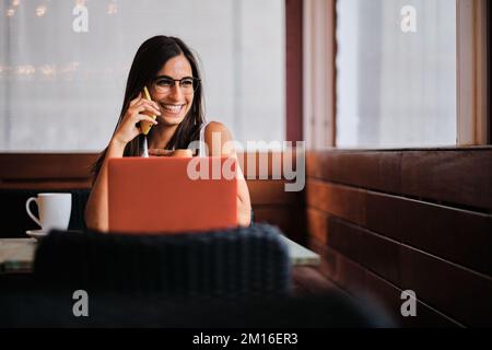 Businesswoman using a mobile while working in a cafeteria Stock Photo