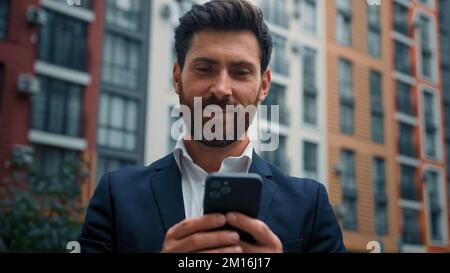 Caucasian handsome professional businessman middle-aged man hold cellphone gadget work online in city outdoor chatting on mobile phone read sms use e Stock Photo