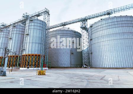 Modern Granary elevator. Silver silos on agro-processing and manufacturing plant for processing drying cleaning and storage of agricultural products, Stock Photo