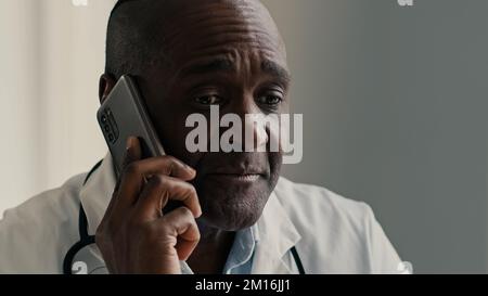 African American ethnic doctor man therapist medical worker consult patient by mobile phone male professional adviser physician speak distant virtual Stock Photo