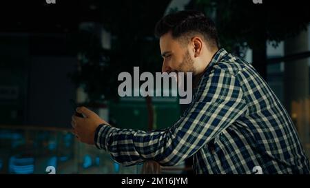 Side view hispanic arabian man stand in shopping mall business center bearded handsome guy client businessman use phone gadget read digital news Stock Photo