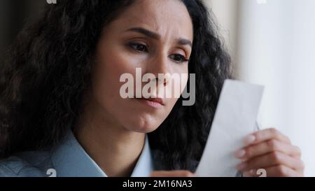 Worried young woman employee feel stressed about high tax looking at unpaid bank debt check costs serious business worker read expenses information lo Stock Photo