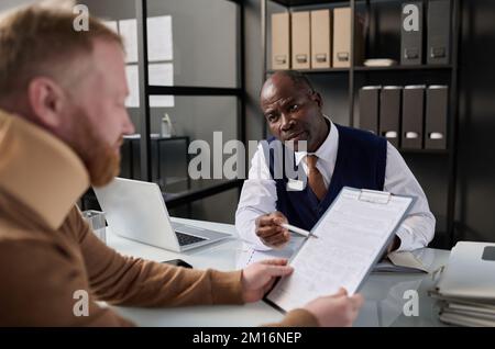 Portrait of black insurance broker consulting man with neck injury after accident Stock Photo