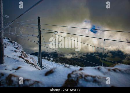 A scenic shot of the lines of a ropeway in a snowy mounts under the cloudy sky Stock Photo
