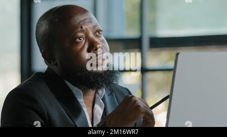 Doubtful thoughtful african american team leader male coach think question solve daily working task in mind has dilemma self brainstorming reflective Stock Photo