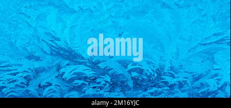 Swirling blue frost patterns on a window pane during a cold morning in winter.. Stock Photo