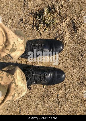 Soldier boots, soldier is standing with black boots on the ground, selective focus. Stock Photo