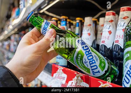 Tuborg beer bottles on shelves in a supermarket. Buyer takes Tuborg beer. Hand is holding Tuborg beer. Minsk, Belarus, 2022 Stock Photo