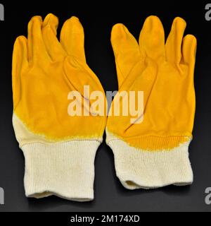 New and yellow protective work gloves isolated on black background Stock Photo
