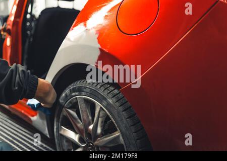 Part of a red car covered with automotive filler. Professional mechanic at work. Repairing and preparation for varnish. . High quality photo Stock Photo