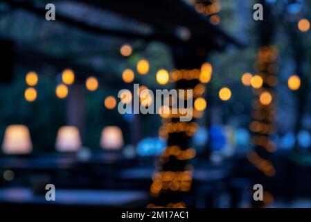Street cafe at night blurred background with bokeh lights. Stock Photo