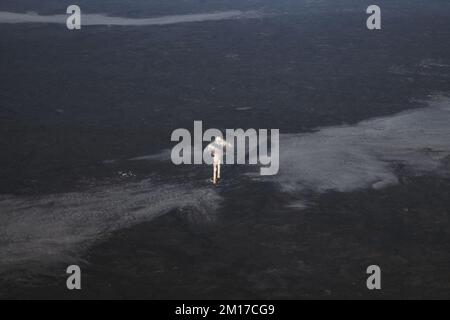 Airplane window view of two huge chimneys of thermal power plant, spewing up grandiose columns of steam or smoke which are casting the shadow on cloud Stock Photo