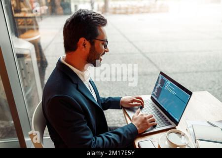 Handsome developer programmer freelancer in glasses working on project in cafe Stock Photo