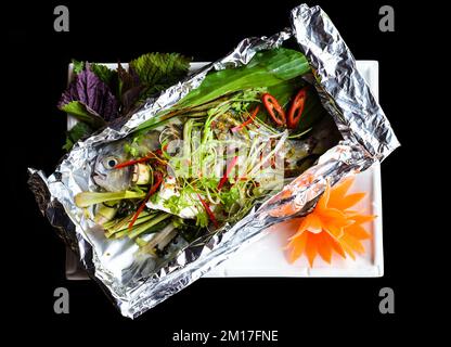 Pampus argenteus fish grilled in Vietnamese style with vegetables isolated on black background top view Stock Photo