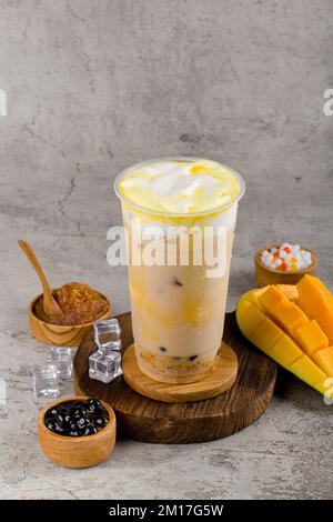 Boba or tapioca pearls is taiwan bubble milk tea in plastic cup with mango caramel flavor on texture  background, summers refreshment. Stock Photo