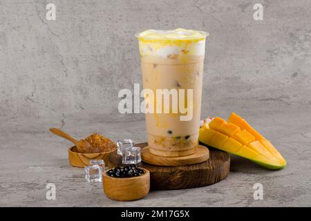 Boba or tapioca pearls is taiwan bubble milk tea in plastic cup with mango caramel flavor on texture  background, summers refreshment. Stock Photo
