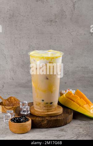 Boba or tapioca pearls is taiwan bubble milk tea in plastic cup with mango caramel flavor on texture  background, summers refreshment. Stock Photo