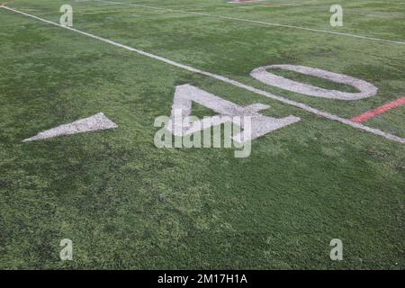 40 yard line on an American, high school football field with white numerals and green turf and an arrow pointing to the left next to the number 4. Stock Photo