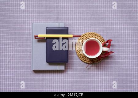 Notebook and pen, cup of black tea on purple check pattern fabric background. flat lay, top view Stock Photo