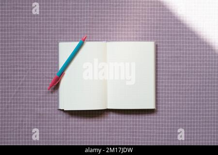Open notebook and pen on purple check pattern fabric background. top view, copy space Stock Photo