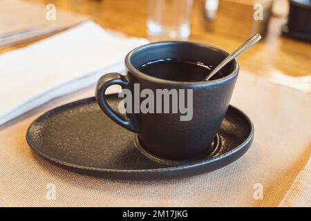 Black tea cup and saucer for drink. Ceramic coffee cup or mug close up. Stock Photo