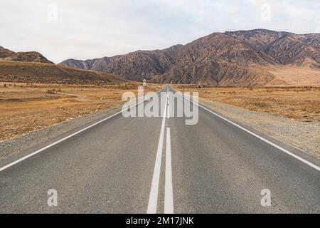 Paved road leading to the mountains. Beautiful mountain landscape on the background. Stock Photo