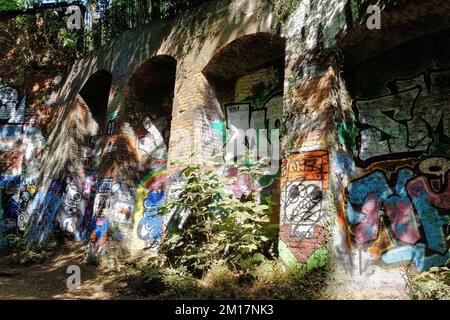 Colourful painted graffiti on old disused railway brick arches in the sun along Parkland Walk near Finsbury, Archway and Highgate, London, England Stock Photo