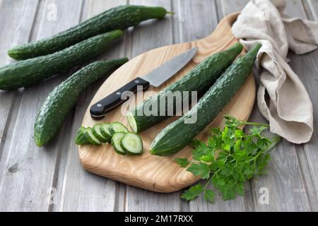 Long Chinese cucumbers on a cutting board while slicing salad. wood background. selective focus Stock Photo