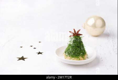 Christmas snack in the form of trees. Delicious cream cheese canapes with nuts, garlic and chopped dill on homemade puff cookies, decorated with a ani Stock Photo
