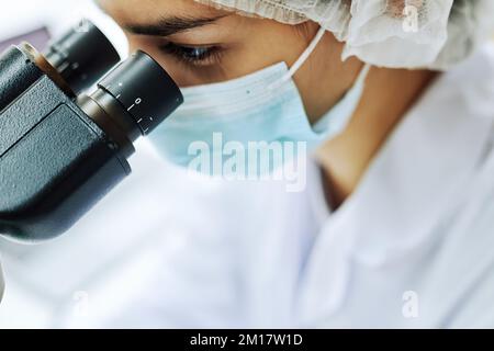 Macro shot of female scientist looking in microscope while working on medical research, with copy space Stock Photo