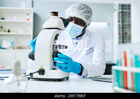 Portrait of African American man using microscope while doing research in medical laboratory Stock Photo