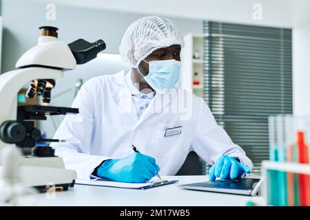 Portrait of adult black man as scientist using laptop while doing research in medical laboratory Stock Photo