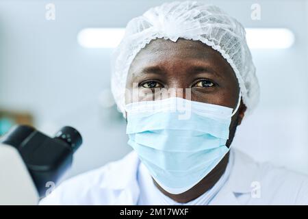 Portrait of black man wearing face mask and looking at camera while working in medical laboratory Stock Photo