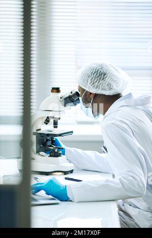 Vertical portrait of male scientist using microscope in medical lab Stock Photo