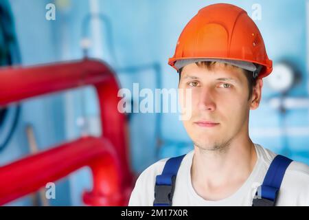 Man in construction helmet looks directly into cell inside room. Authentic portrait of real gas worker.. Stock Photo