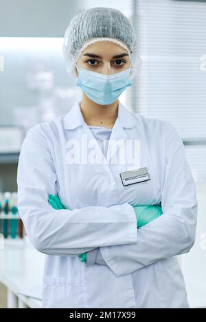 Vertical Portrait of Middle Eastern female scientist standing in medical laboratory and posing with arms crossed Stock Photo