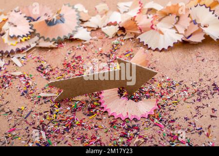 Arrow cut out of paper amid pencil shavings on canvas Stock Photo