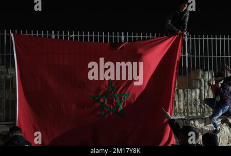 JERUSALEM, ISRAEL - DECEMBER 10: Young Palestinians hang a large Moroccan flag, as they celebrate Morocco's victory against Portugal after the FIFA World Cup Qatar 2022 Quarter Final match between Morocco and Portugal, in the old city on December 10, 2022 in Jerusalem, Israel. Morocco becomes first African side to enter FIFA World Cup semifinal after Portugal in Qatar. Credit: Eddie Gerald/Alamy Live News Stock Photo