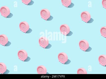 A pattern of pink alarm clocks on a bright pastel blue background. Stock Photo