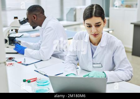 Portrait of young Middle Eastern woman using laptop in laboratory while working on medical research Stock Photo