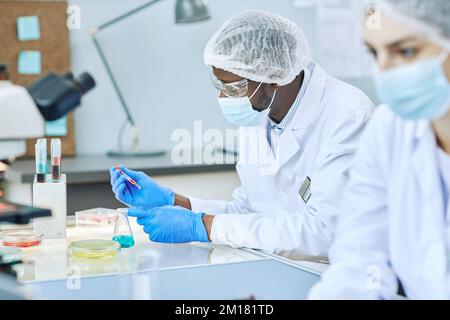 Side view portrait of black man working in modern laboratory and doing blood tests Stock Photo