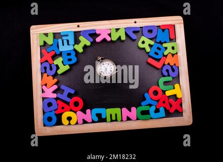 Pocket watch and colorful Letters of Alphabet made of wood Stock Photo