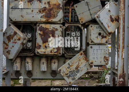 Old abandoned industrial electrical switchboard with heavy rust, broken covers and ceramic fuses Stock Photo