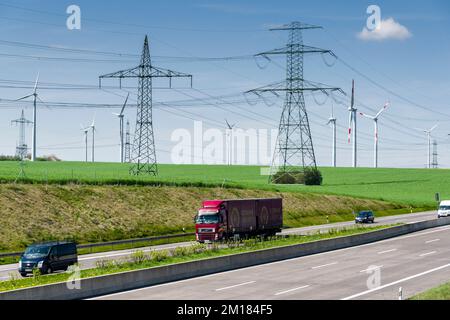 Agricultural landscape with overhead powerlines, cars on a highway and green fields Stock Photo